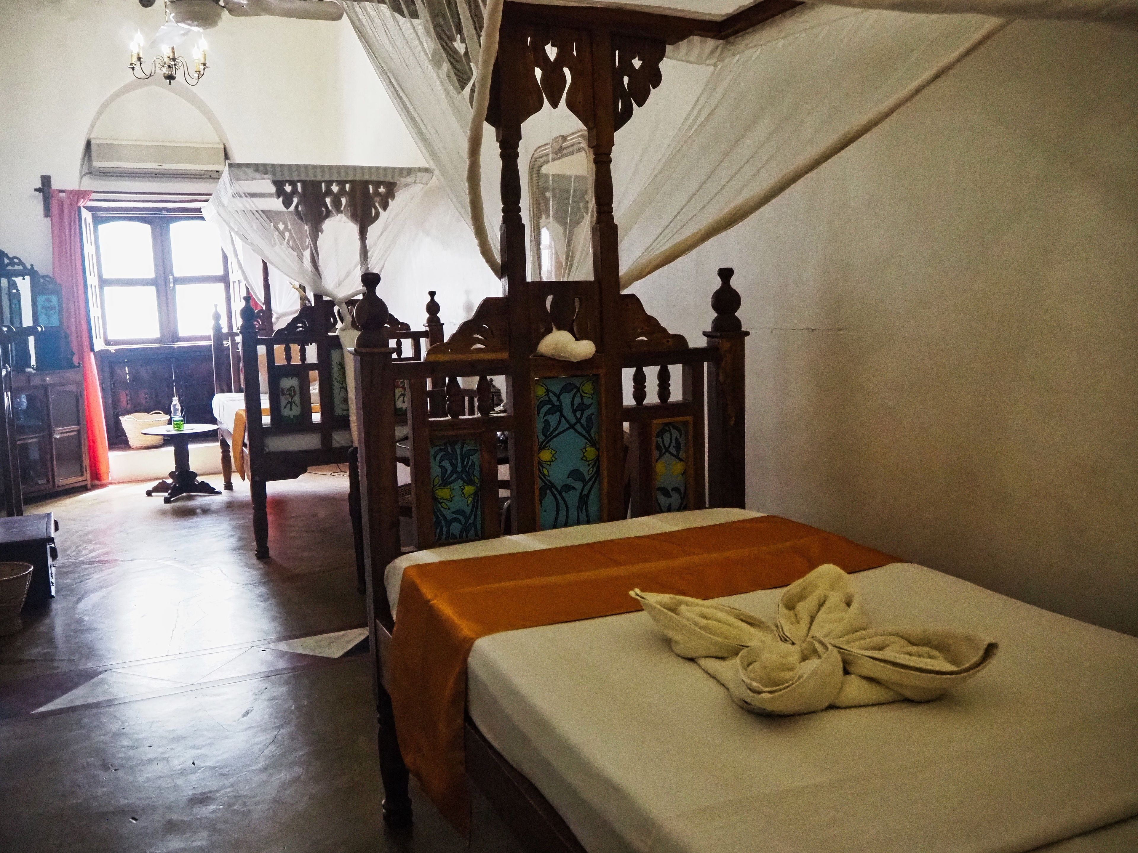 A traditional room with a wooden bed, a small table, and a chair.
