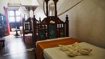 A traditional room with a wooden bed, a small table, and a chair.