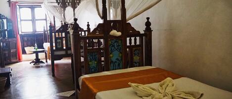 A traditional room with a wooden bed, a small table, and a chair.