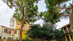 A courtyard with a church tower, a yellow building, and a tree. - Welc-oM Prato della Valle (Padova)