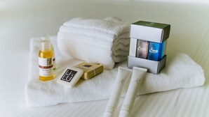 A neatly arranged set of toiletries on a white towel, including a bottle, a bar of soap, and two tubes, likely for a hotel room setting. - Welc-oM Prato della Valle (Padova)