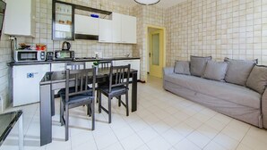 A compact kitchen with a dining table and chairs, a microwave, a kettle, and a built-in oven. - Welc-oM Prato della Valle (Padova)