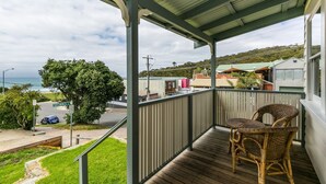 Ein Balkon mit Korbmöbeln, Blick auf die Straße und ein Gebäude mit grüner Dachbegrünung.