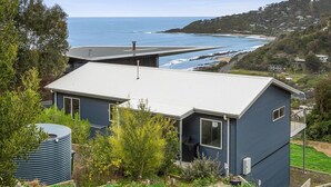 A coastal property with a modern house, a large water tank, and a view of the ocean.