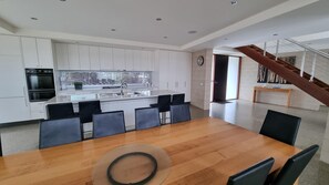 Una cucina moderna con mobili bianchi, un'isola centrale e un'area pranzo con tavolo in legno e sedie nere.
