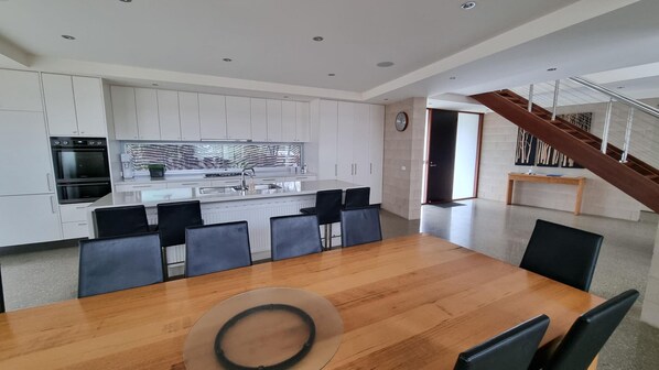 A modern kitchen with white cabinets, a central island, and a dining area with a wooden table and black chairs.