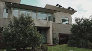 Ein modernes, zweistöckiges Haus mit großen Fenstern, einer flachen Dachkonstruktion und einem gepflegten Garten.