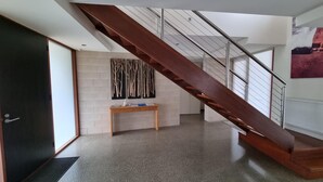 Ein modernes Interieur mit einer Holztreppe, einem kleinen Holztisch und einem an der Wand befestigten Kunstwerk.