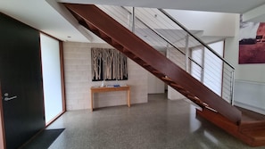 A modern interior with a wooden staircase, a small wooden table, and a wall-mounted artwork.