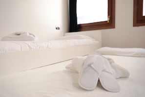 A hotel room with two beds, one with a white duvet and the other with a white blanket.