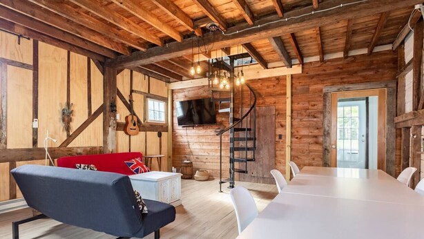 Un interior rústico de madera con un sofá, una mesa de comedor y un televisor montado en la pared.