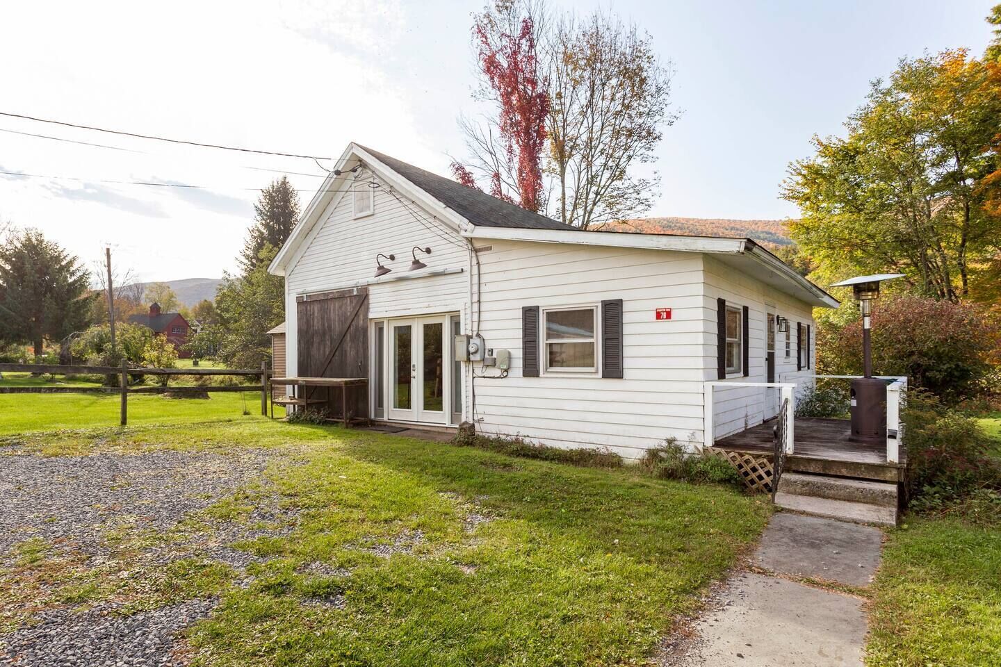 A single-story white house with a front porch, a garage, and a small deck.