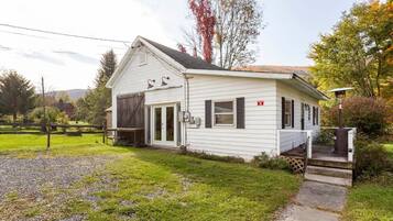 A single-story white house with a front porch, a garage, and a small deck.