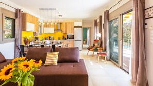 Een moderne woonkamer met een bank, een eethoek en een keuken op de achtergrond.