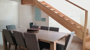 A dining area with a wooden table and chairs, a staircase, and a wall with a motivational quote. - Lonsdale Shores in Point Lonsdale (Point Lonsdale)
