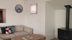 A living room with a sofa, a coffee table, a clock, a window, and a fireplace. - Lonsdale Shores in Point Lonsdale (Point Lonsdale)