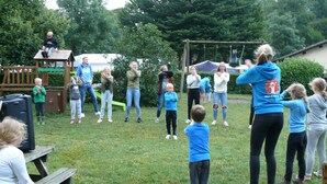 Eine Gruppe von Menschen ist draußen versammelt, vermutlich in einem Park oder Erholungsgebiet.