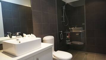 A modern bathroom with a white sink, toilet, and shower.