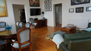 A living room with a sofa, chairs, a TV, and artwork on the walls. - Ozone Tower in Queenscliff (Queenscliffe)