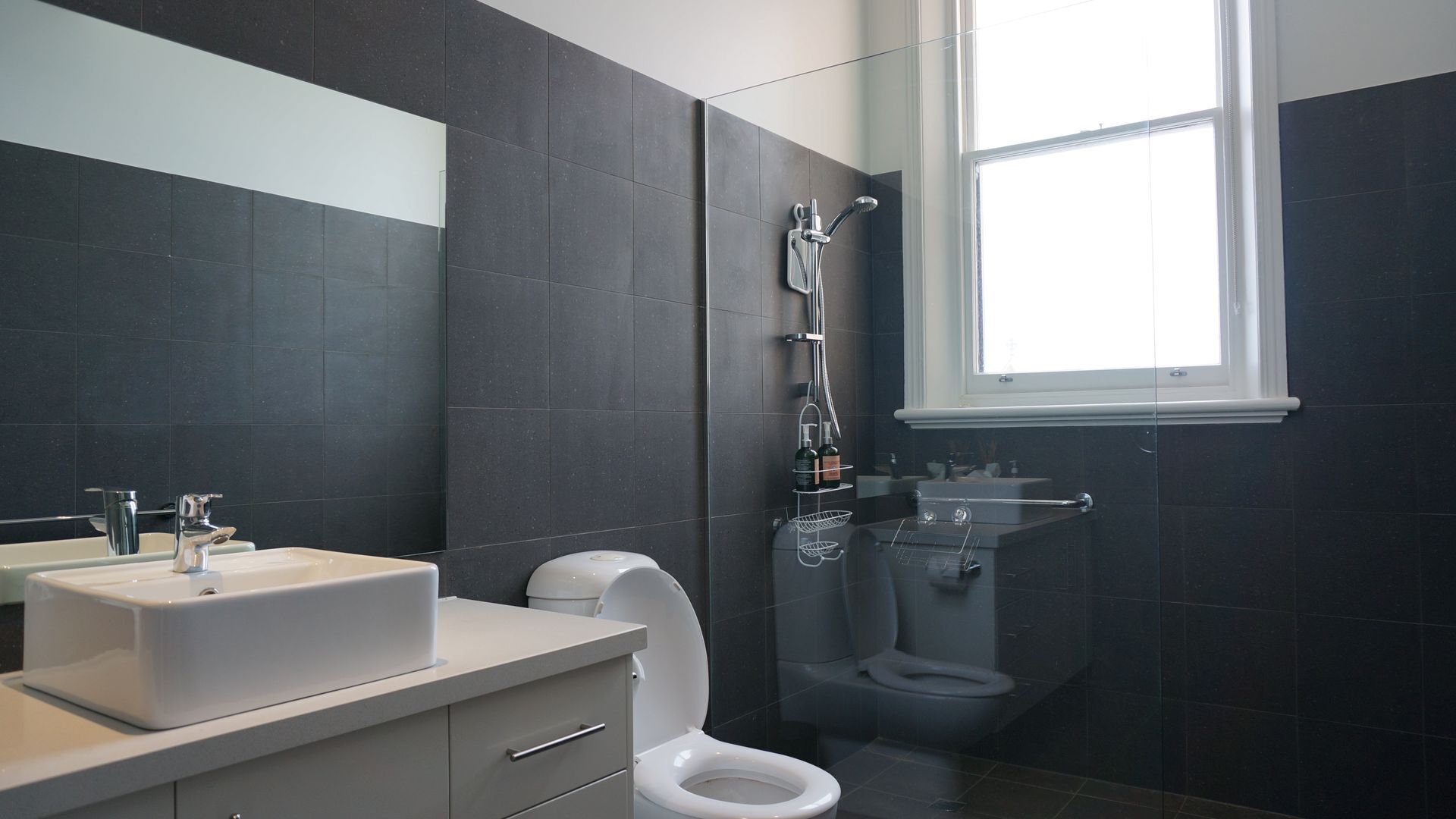 A modern bathroom with a sink, toilet, and shower.
