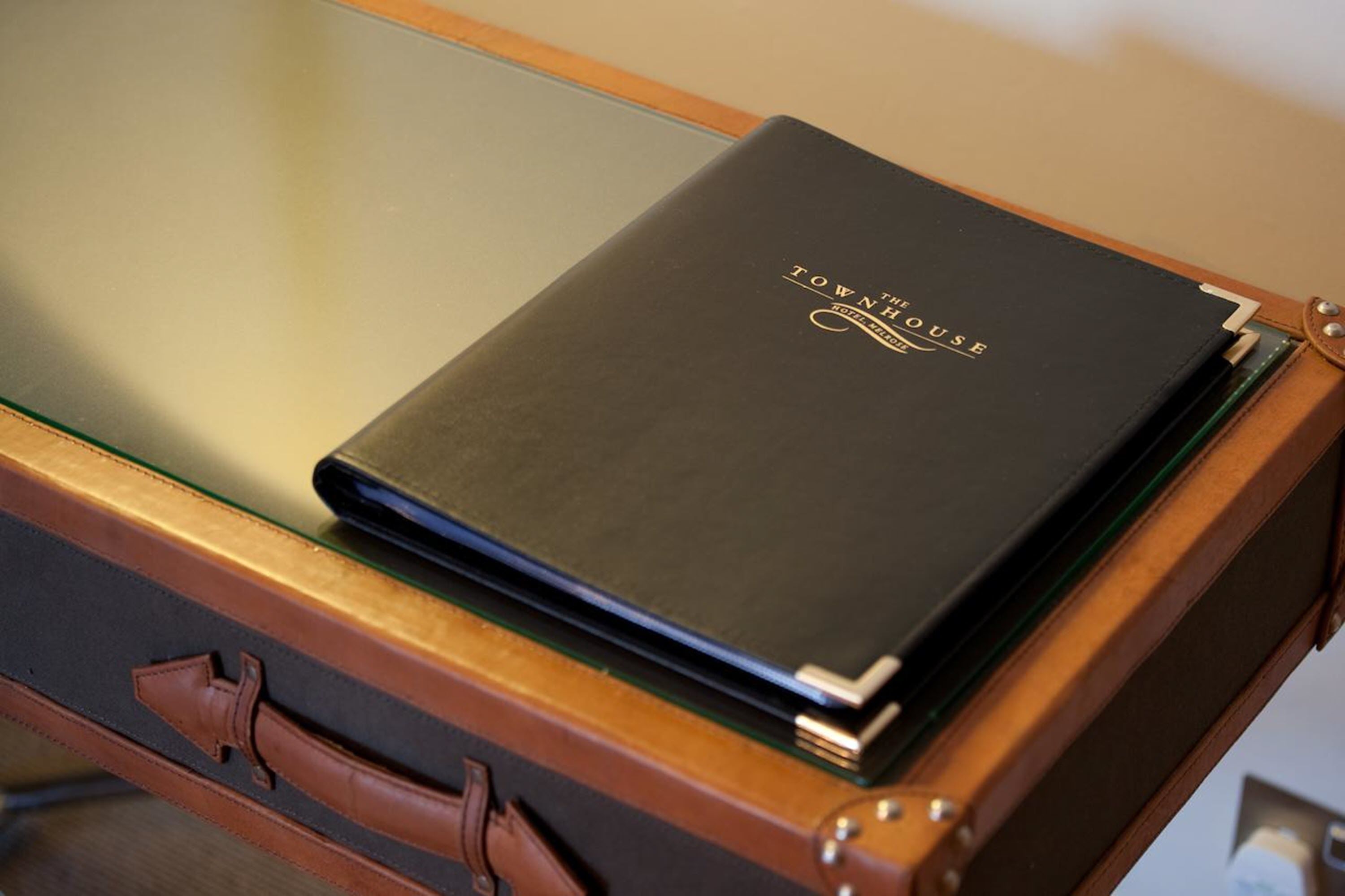 A black book titled "THE HOUSE" on a wooden table.