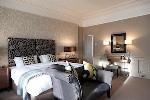Habitación de hotel con una cama grande, un sofá, un escritorio y un espejo.