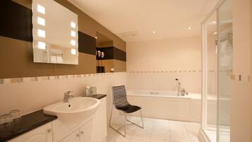 A bathroom with a large mirror, a sink, a chair, and a bathtub.