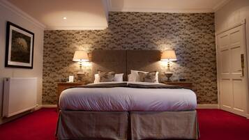 A bedroom with a large bed, two bedside lamps, a radiator, and a door.