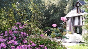 Ein Garten mit rosa Blumen und ein Haus mit schrägem Dach.