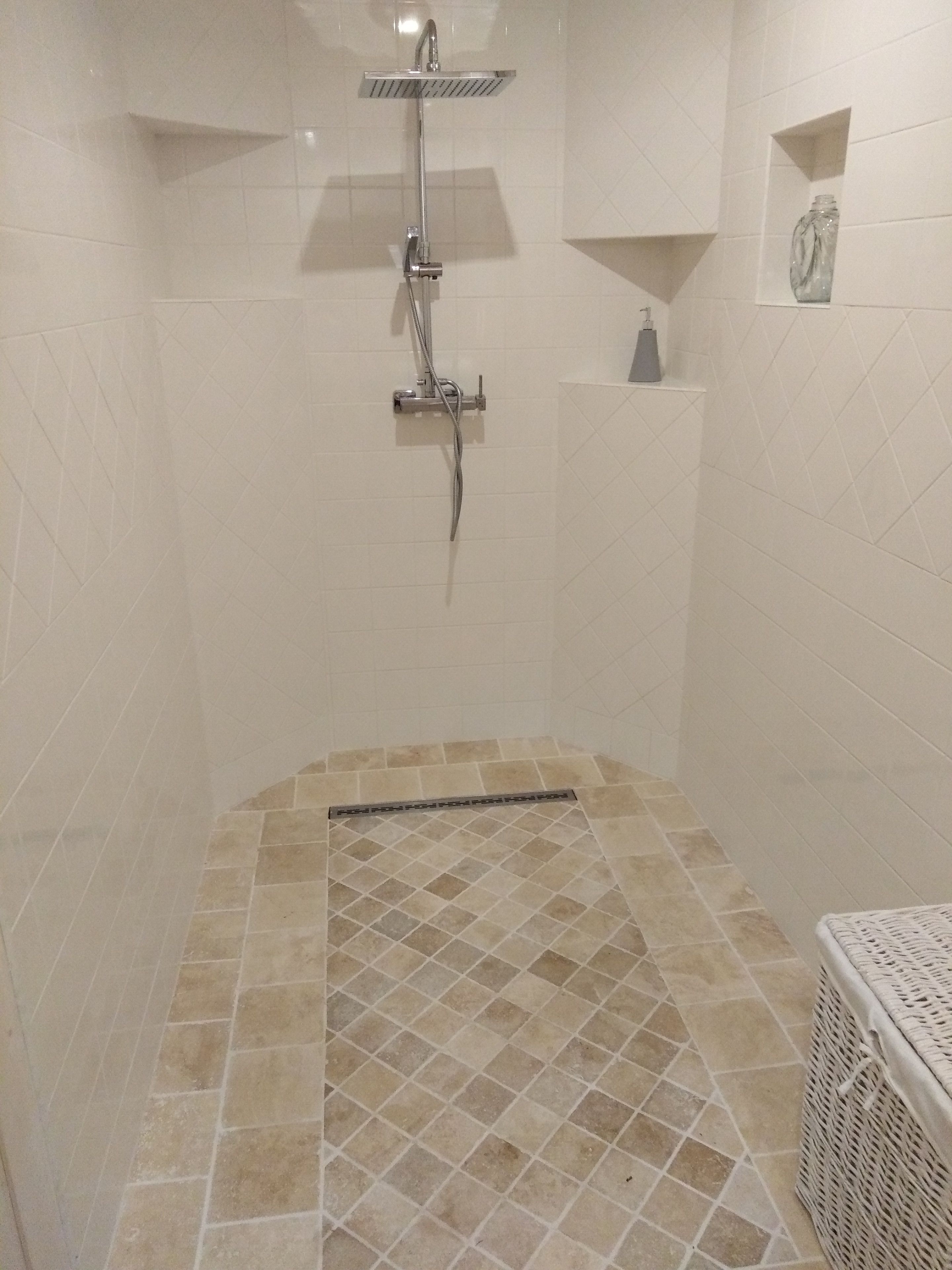 A shower with a tiled floor and a wall-mounted showerhead.