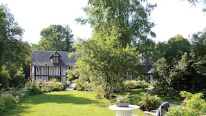 Ein traditionelles Haus im Tudor-Stil mit einem gepflegten Garten, einer Rasenfläche und einem hölzernen Schaukelstuhl.