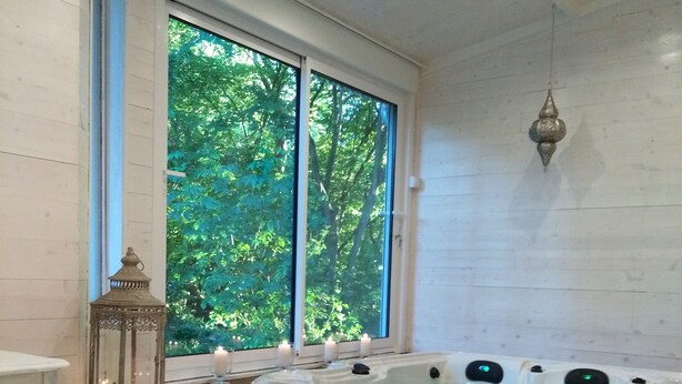 Ein Spa-Raum mit einem großen Fenster, einer Whirlwanne, einem Korbwannen mit Handtüchern und einem weißen Fellteppich.