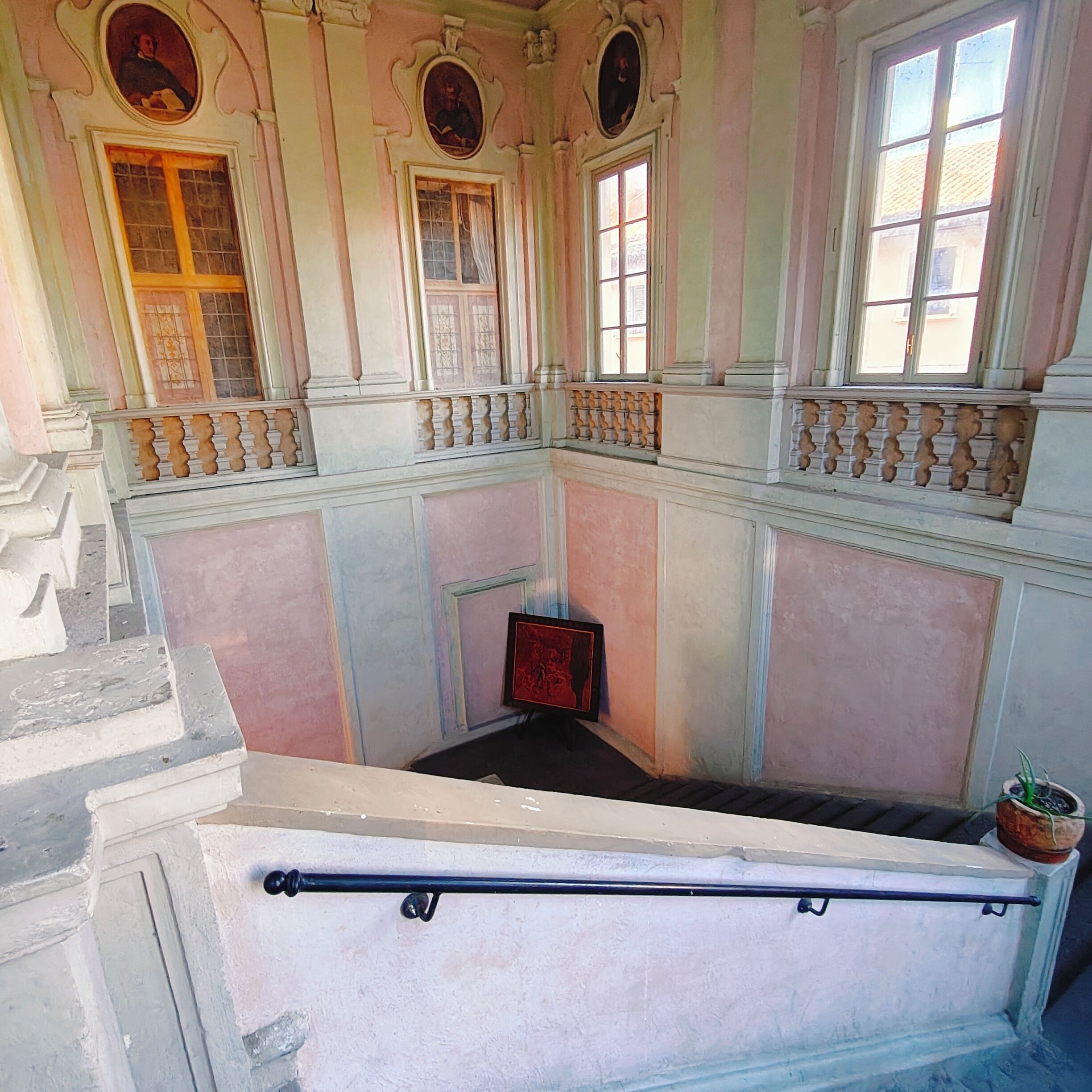 Um quarto com lareira central, varanda com guarda-corpo e janela com vista.