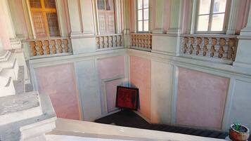 Um quarto com lareira central, varanda com guarda-corpo e janela com vista.