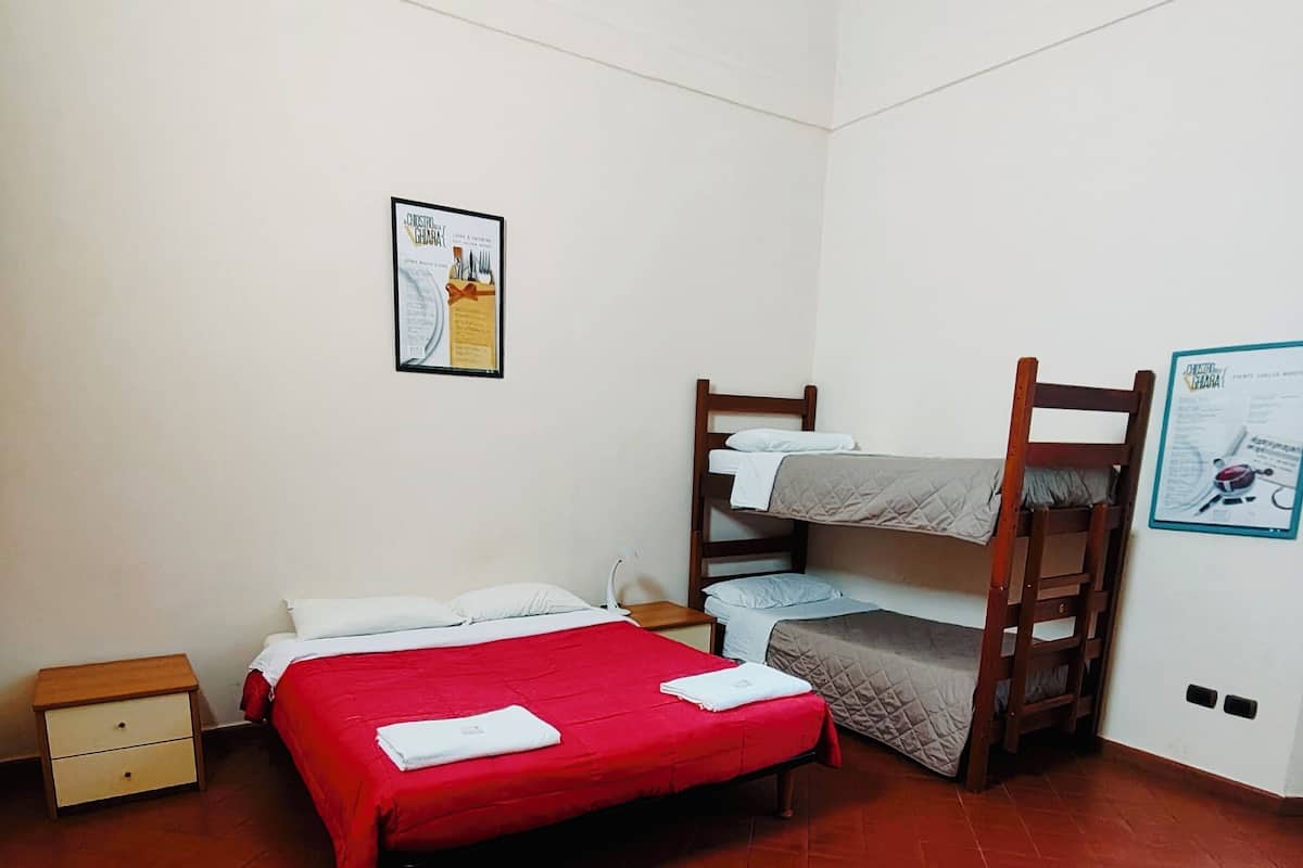 A room with a bunk bed, a single bed, a nightstand, and a poster on the wall.