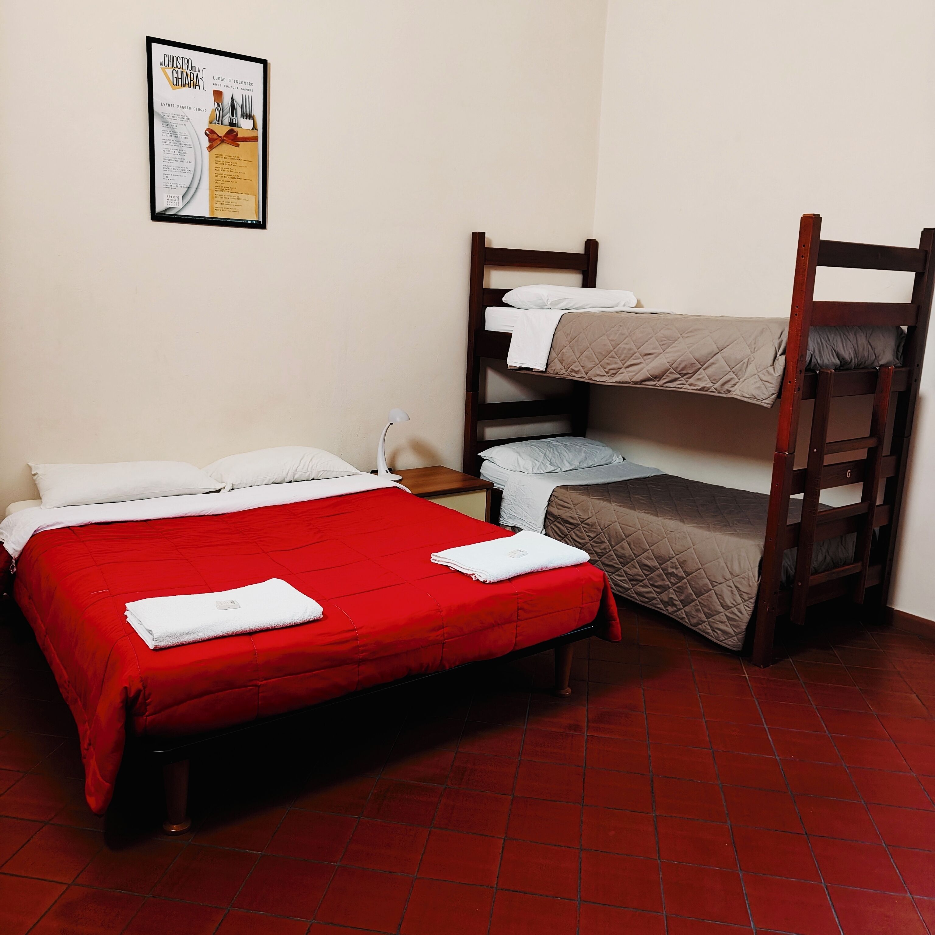 A room with a bunk bed, a single bed, and a nightstand.