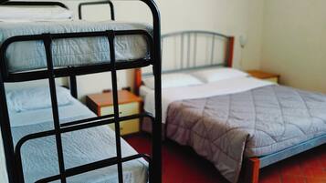 Una camera del dormitorio con letti a castello, un letto singolo, un comodino e un punto luce fissato al muro.