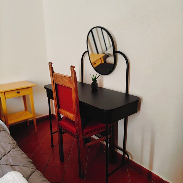 Una habitación pequeña con una silla de madera, una mesa negra y un espejo en la pared.