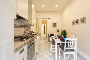 A kitchen with a stove, sink, and cabinets, leading to a dining area with a table and chairs.