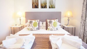 A neatly made bed with two pillows, two bedside lamps, and a clock on the nightstand. - The Old Dairy Farm B&B (Emsworth)