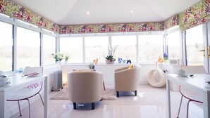 A bright, sunlit room with a large window, a white table, two chairs, and a radiator. - The Old Dairy Farm B&B (Emsworth)