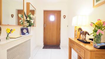A hotel reception area with a wooden desk, a mirror, a clock, and a door.