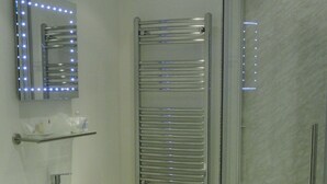 A bathroom with a sink, mirror, towel rack, toilet, and a glass-enclosed shower. - The Old Dairy Farm B&B (Emsworth)