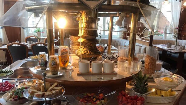 A buffet with various food items including fruits, bread, and beverages.