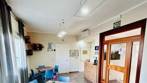 Habitación de hotel con comedor que incluye una mesa de madera y sillas azules, una kitchenette y una puerta de madera con espejo.