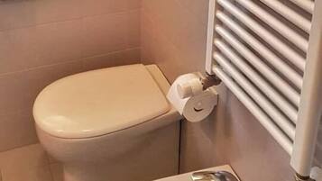 Ein Badezimmer mit Toilette, Waschbecken, Handtuchhalter und einem Fenster.