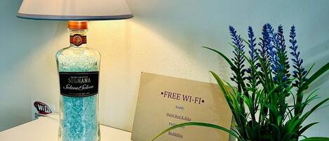 A reception desk with a lamp, a sign offering free Wi-Fi, a name tag, and a potted plant.