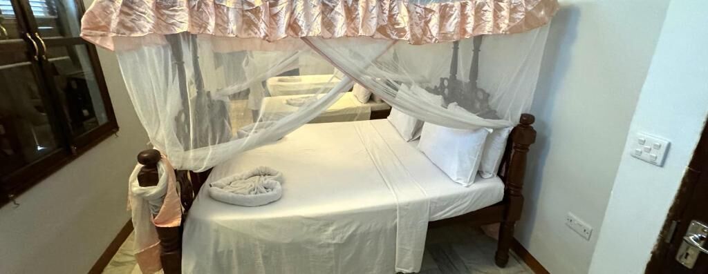 Una cama con dosel, una mesita de noche y una silla.