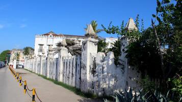 A street with a white wall and a chain-link fence.