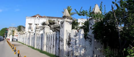 A street with a white wall and a chain-link fence.